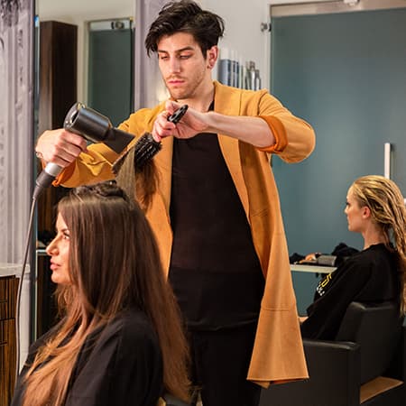 Tyler Bush styling a client's hair at Triune Salon